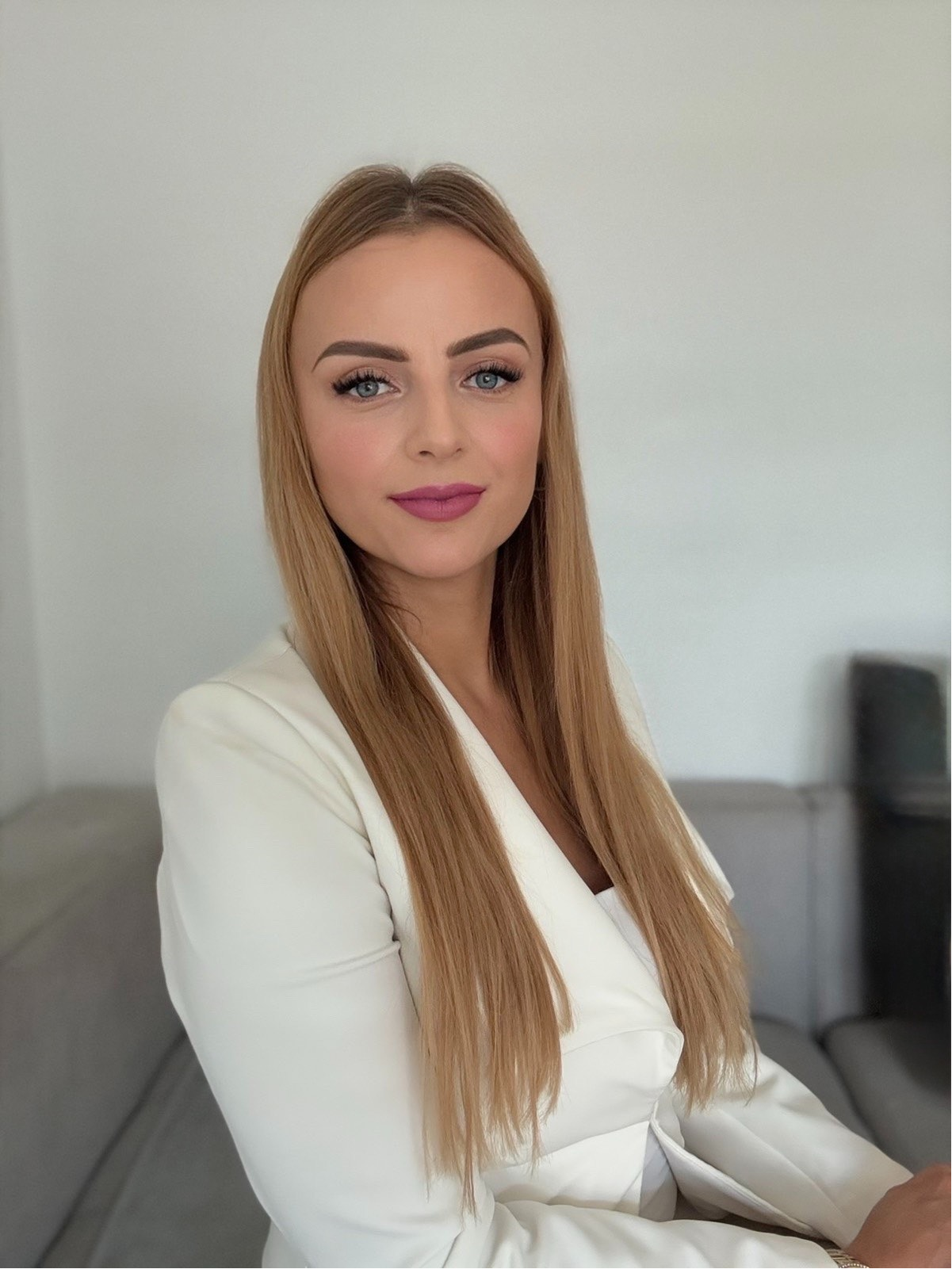 Portrait of Slađana Stanković in a white blazer in front of a light-coloured wall.