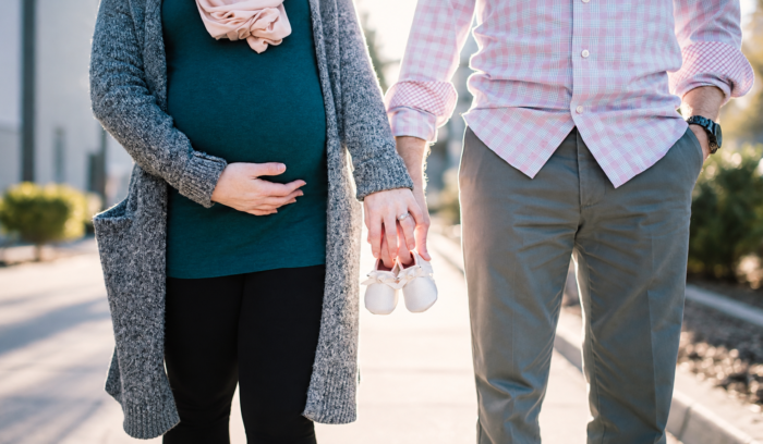 woman and man holding hands and walking in the nature woman is pregnant